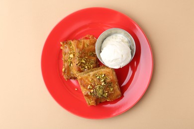 Photo of Tasty baklava with chopped nuts and scoop of ice cream on beige table, top view