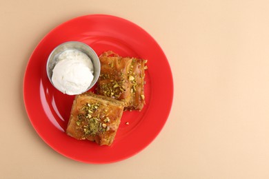 Photo of Tasty baklava with chopped nuts and scoop of ice cream on beige table, top view. Space for text