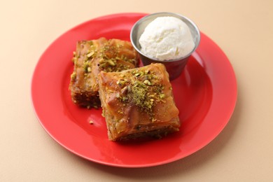 Photo of Tasty baklava with chopped nuts and scoop of ice cream on beige table, closeup