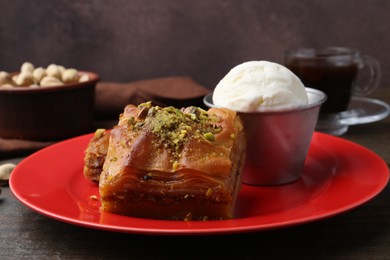 Photo of Tasty baklava with chopped nuts and scoop of ice cream on wooden table, closeup