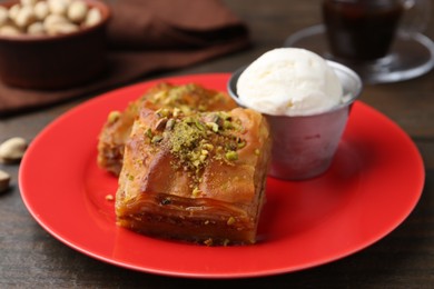 Photo of Tasty baklava with chopped nuts and scoop of ice cream on wooden table, closeup