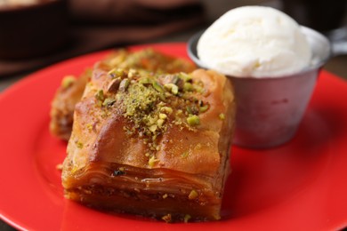 Photo of Tasty baklava with chopped nuts and scoop of ice cream on table, closeup