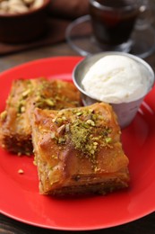 Photo of Tasty baklava with chopped nuts and scoop of ice cream on table, closeup