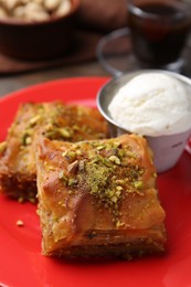 Photo of Tasty baklava with chopped nuts and scoop of ice cream on table, closeup