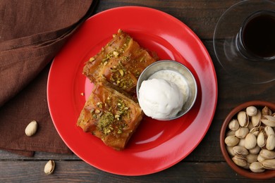 Photo of Tasty baklava with nuts, scoop of ice cream and tea on wooden table, flat lay