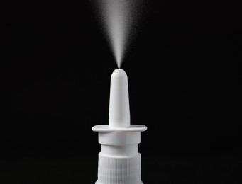 Image of Nasal spray with sprinkled medication over nozzle on black background, closeup