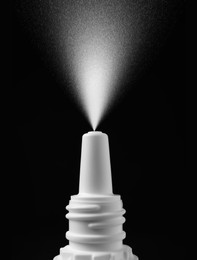 Image of Nasal spray with sprinkled medication over nozzle on black background, closeup