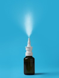 Image of Nasal spray with sprinkled medication over nozzle on light blue background