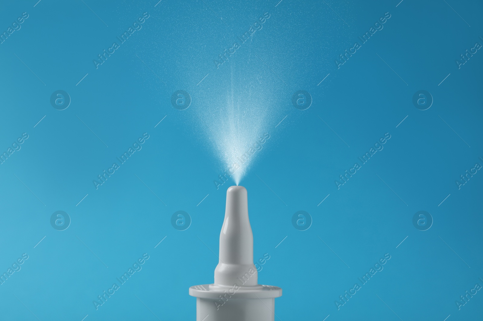 Image of Nasal spray with sprinkled medication over nozzle on light blue background, closeup