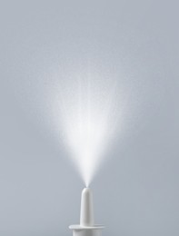 Image of Nasal spray with sprinkled medication over nozzle on grey background, closeup