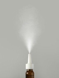 Image of Nasal spray with sprinkled medication over nozzle on grey background, closeup