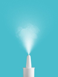 Image of Nasal spray with sprinkled medication over nozzle on light blue background, closeup