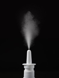 Image of Nasal spray with sprinkled medication over nozzle on black background, closeup