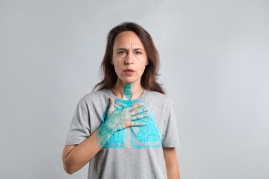 Woman with asthma suffering from difficulty breathing on grey background. Illustration of lungs