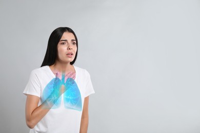 Woman with asthma suffering from difficulty breathing on grey background, space for text. Illustration of lungs