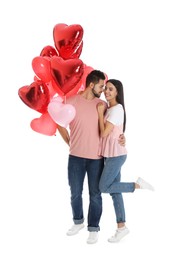 Photo of Happy young couple with heart shaped balloons isolated on white. Valentine's day celebration