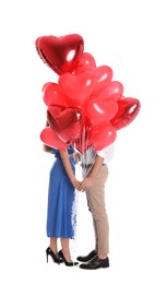 Photo of Young couple hiding behind heart shaped balloons isolated on white. Valentine's day celebration