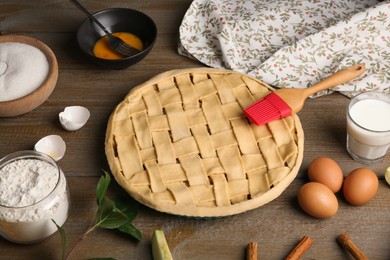 Photo of Uncooked homemade apple pie and ingredients on wooden table