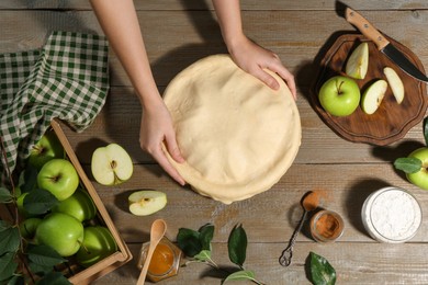 Photo of Woman making homemade apple pie at wooden table, top view