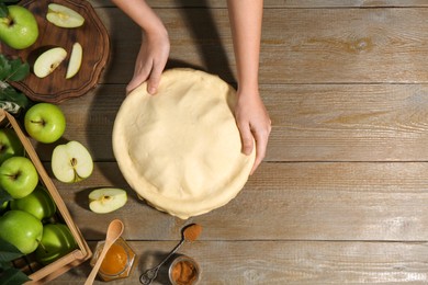 Photo of Woman making homemade apple pie at wooden table, top view. Space for text