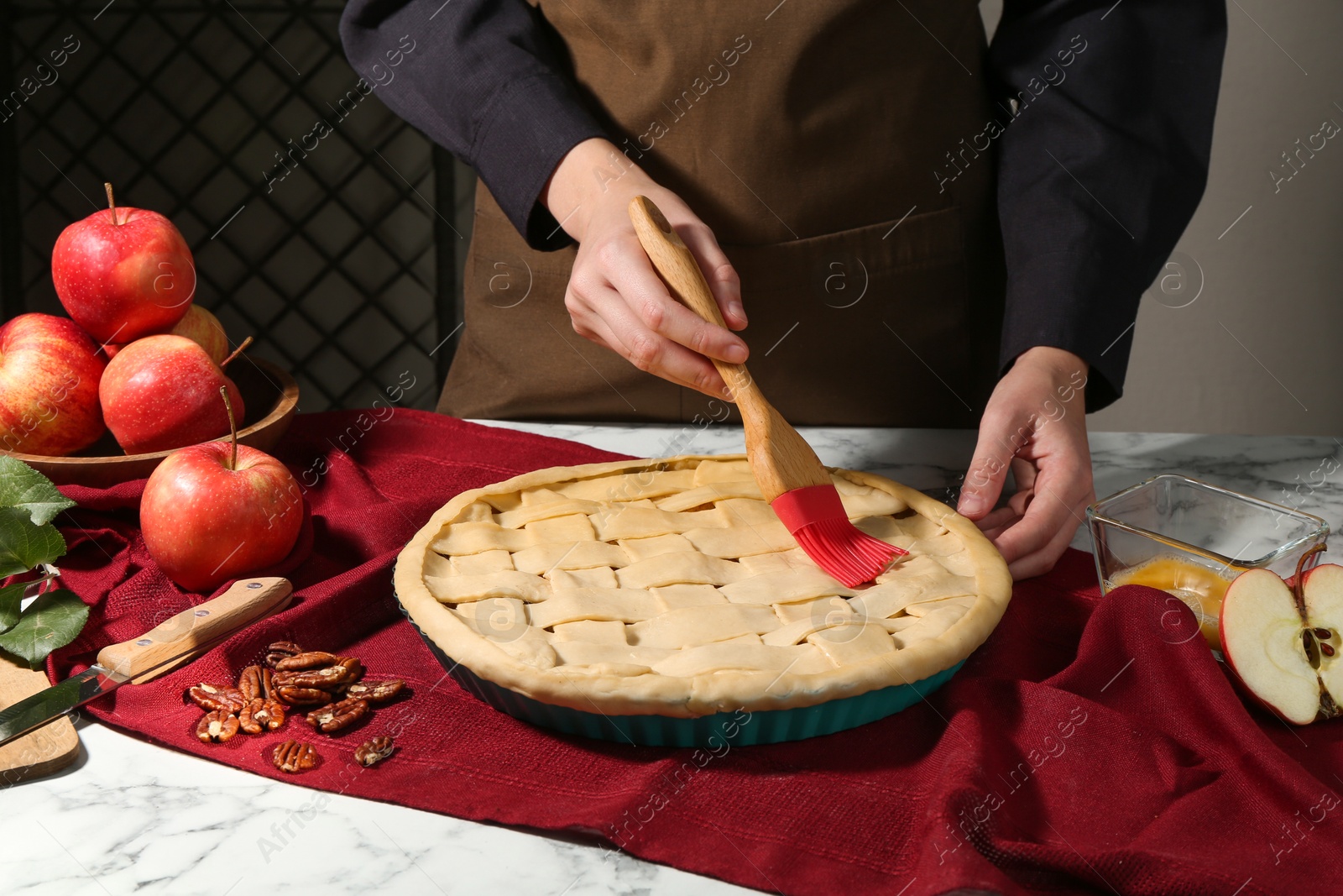 Photo of Woman making homemade apple pie at white marble table, closeup