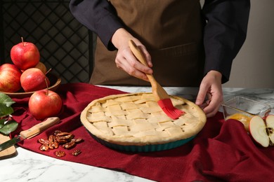 Photo of Woman making homemade apple pie at white marble table, closeup