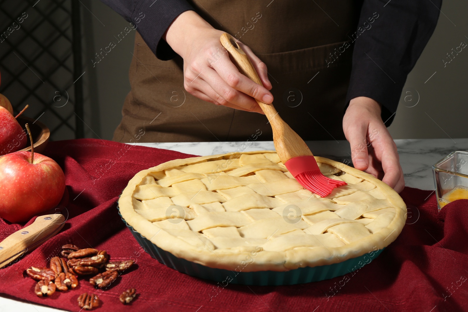 Photo of Woman making homemade apple pie at white marble table, closeup