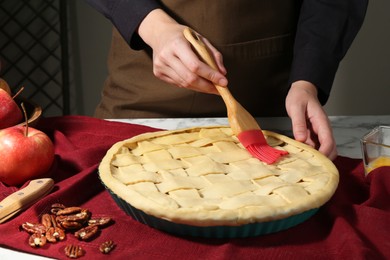 Photo of Woman making homemade apple pie at white marble table, closeup