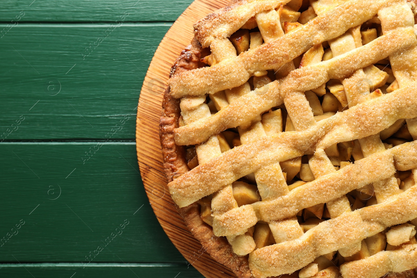 Photo of Tasty homemade apple pie on green wooden table, top view. Space for text