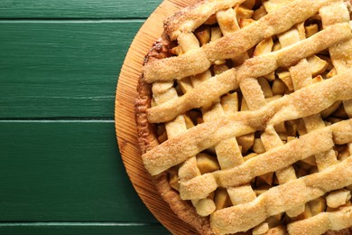 Photo of Tasty homemade apple pie on green wooden table, top view. Space for text