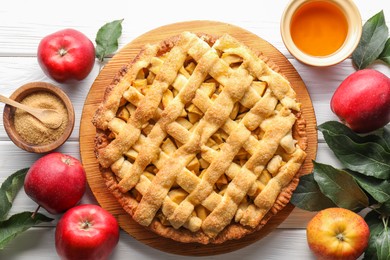 Photo of Tasty homemade apple pie and ingredients on white wooden table, flat lay