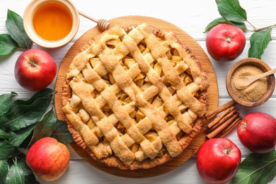 Photo of Tasty homemade apple pie and ingredients on white wooden table, flat lay