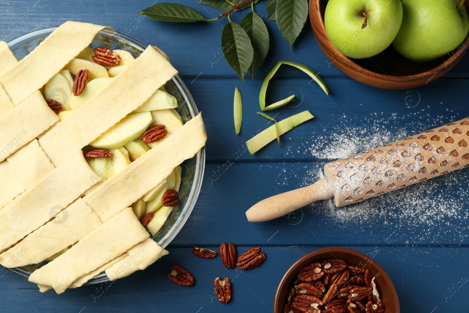 Photo of Flat lay composition with raw homemade apple pie and ingredients on blue wooden table