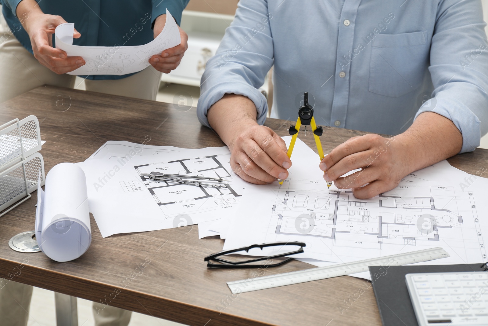 Photo of Architects working with project, closeup. Different technical drawings on wooden table