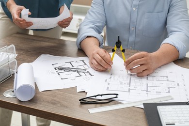 Photo of Architects working with project, closeup. Different technical drawings on wooden table