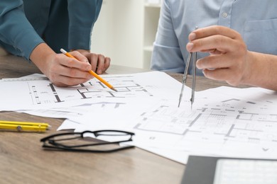 Photo of Architects working with project, closeup. Different technical drawings on wooden table