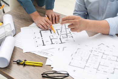 Photo of Architects working with project, closeup. Different technical drawings on wooden table