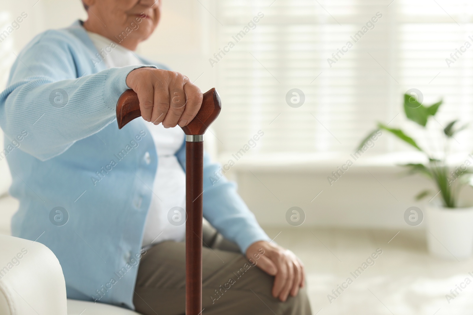 Photo of Lonely senior woman with walking cane indoors, closeup. Space for text