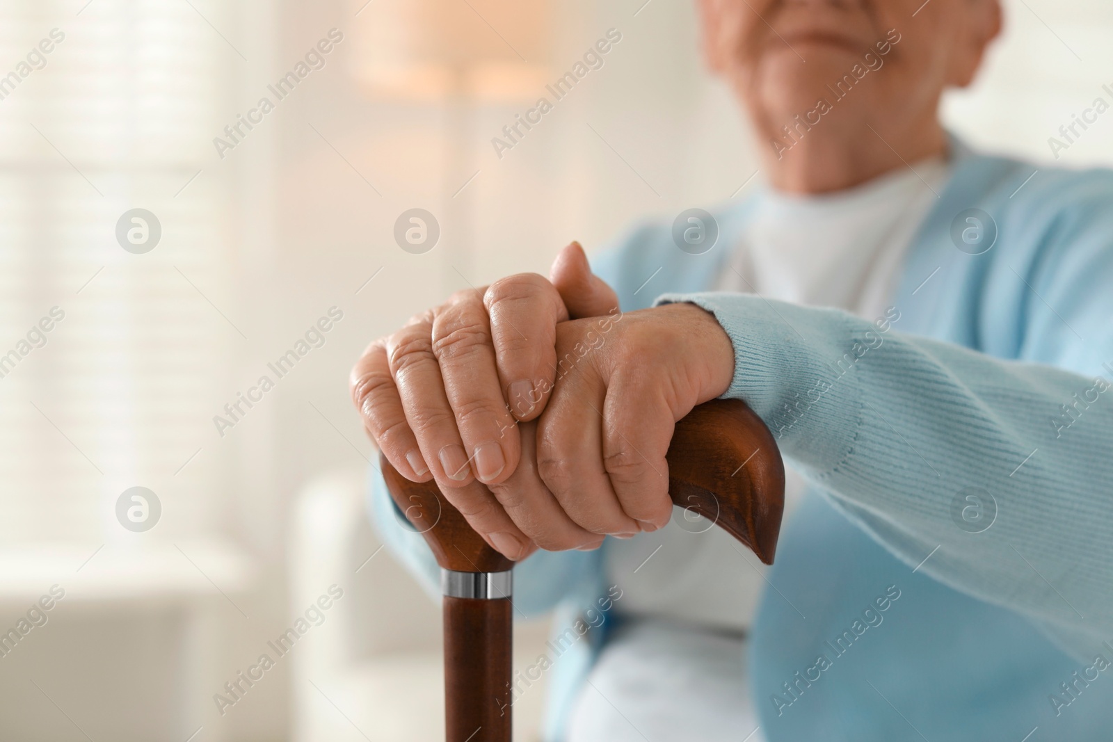 Photo of Lonely senior woman with walking cane indoors, closeup. Space for text