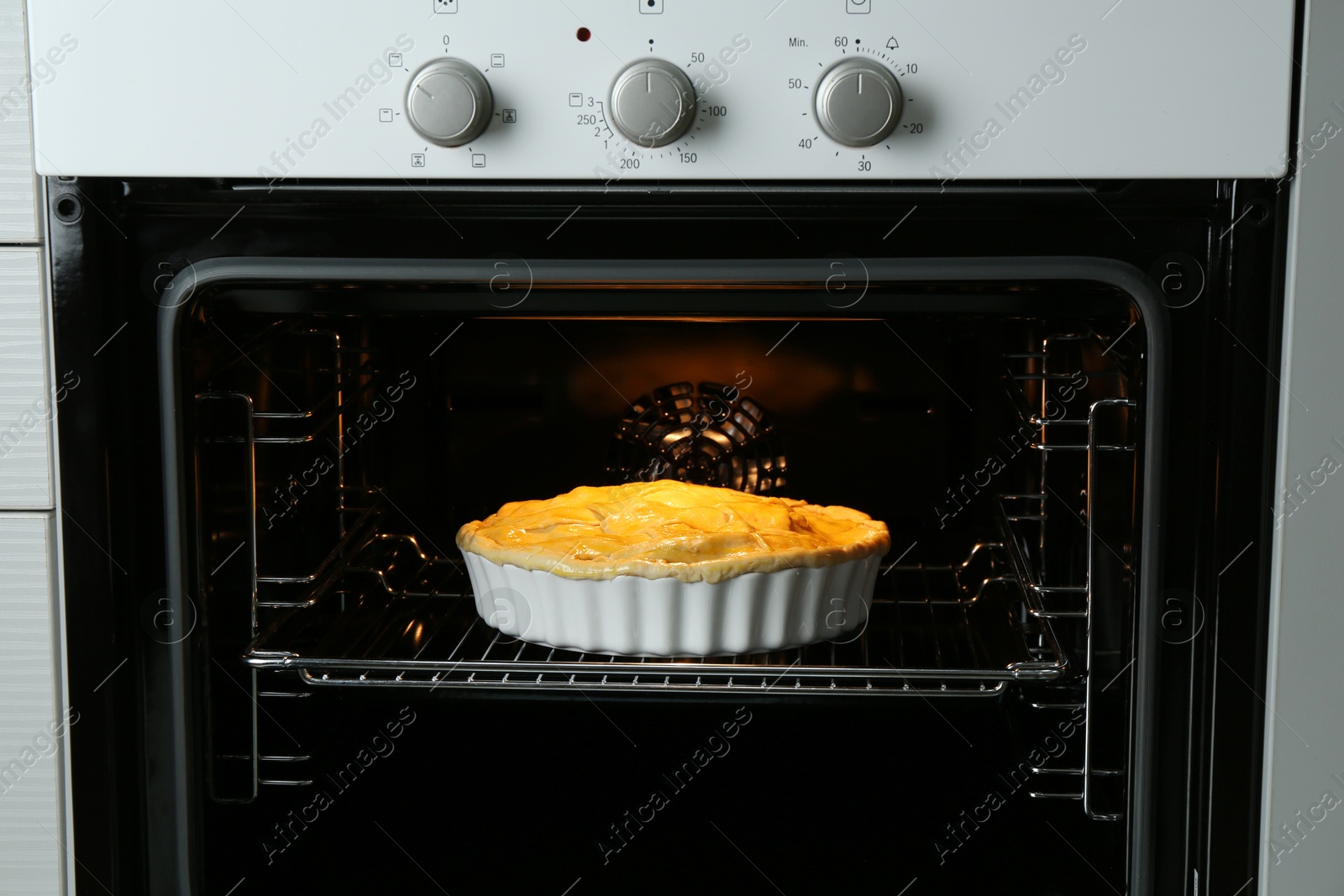 Photo of Baking dish with raw homemade apple pie in oven