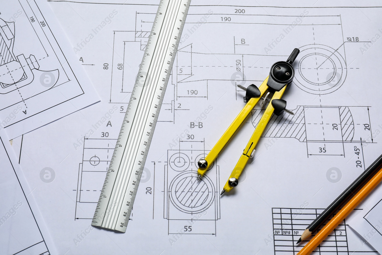 Photo of Different engineering drawings, pencils, ruler and divider on table, flat lay