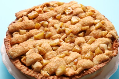 Photo of Tasty homemade apple pie on light blue background, closeup