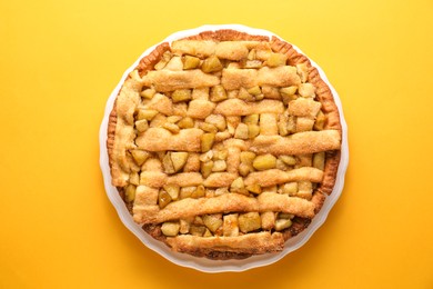 Photo of Tasty homemade apple pie on yellow background, top view