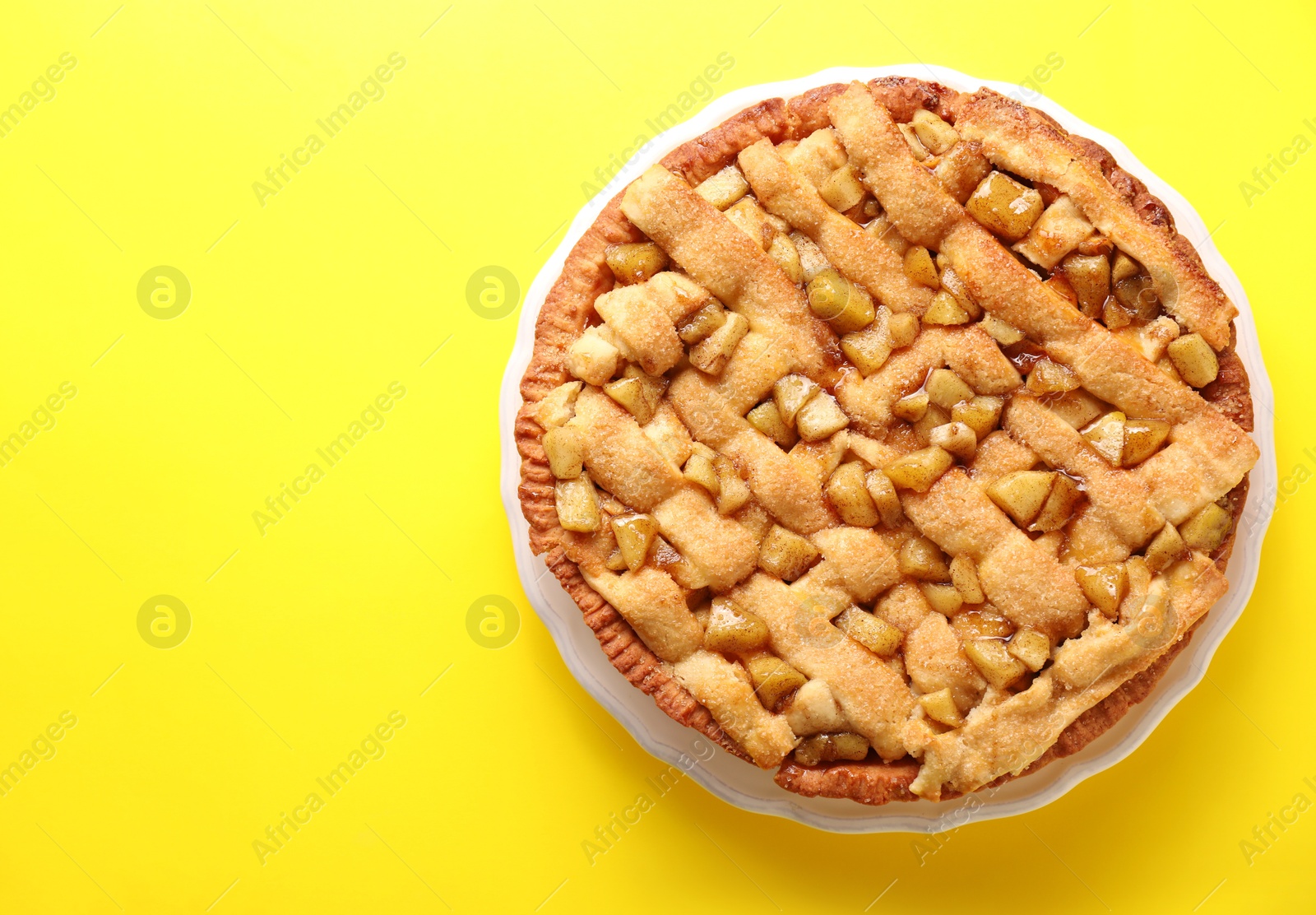 Photo of Tasty homemade apple pie on yellow background, top view. Space for text