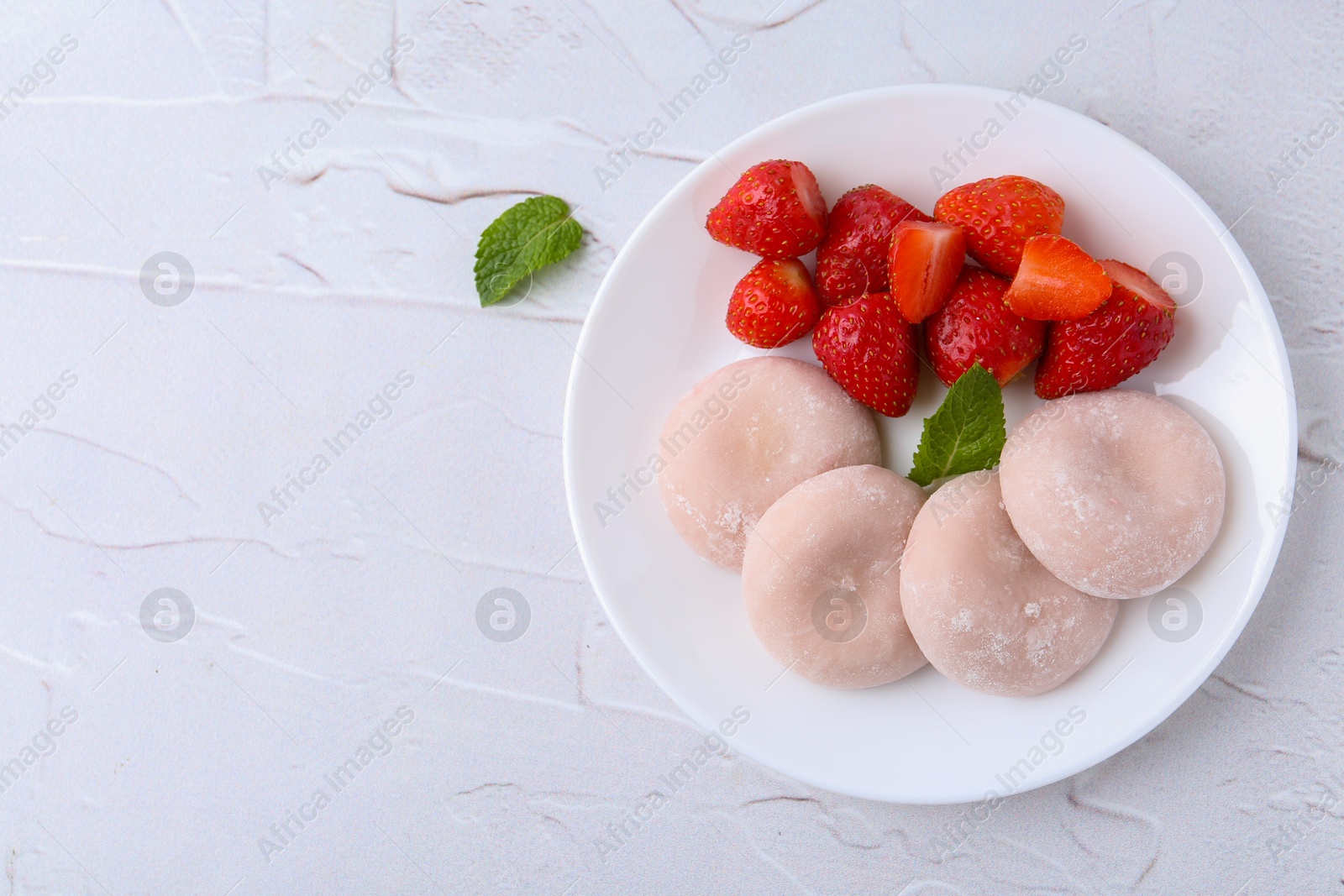 Photo of Delicious mochi and strawberries on white table, top view. Space for text