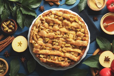 Photo of Homemade apple pie and ingredients on blue wooden table, flat lay