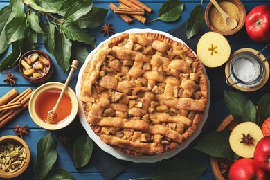 Photo of Homemade apple pie and ingredients on blue wooden table, flat lay