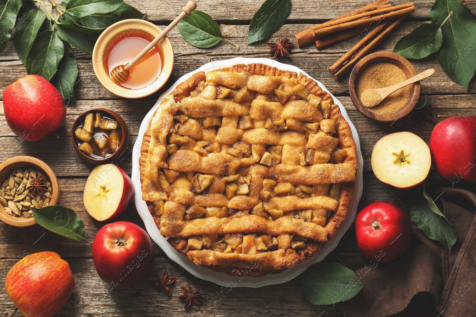 Photo of Homemade apple pie and ingredients on wooden table, flat lay