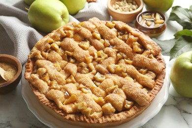 Photo of Homemade apple pie and ingredients on white marble table