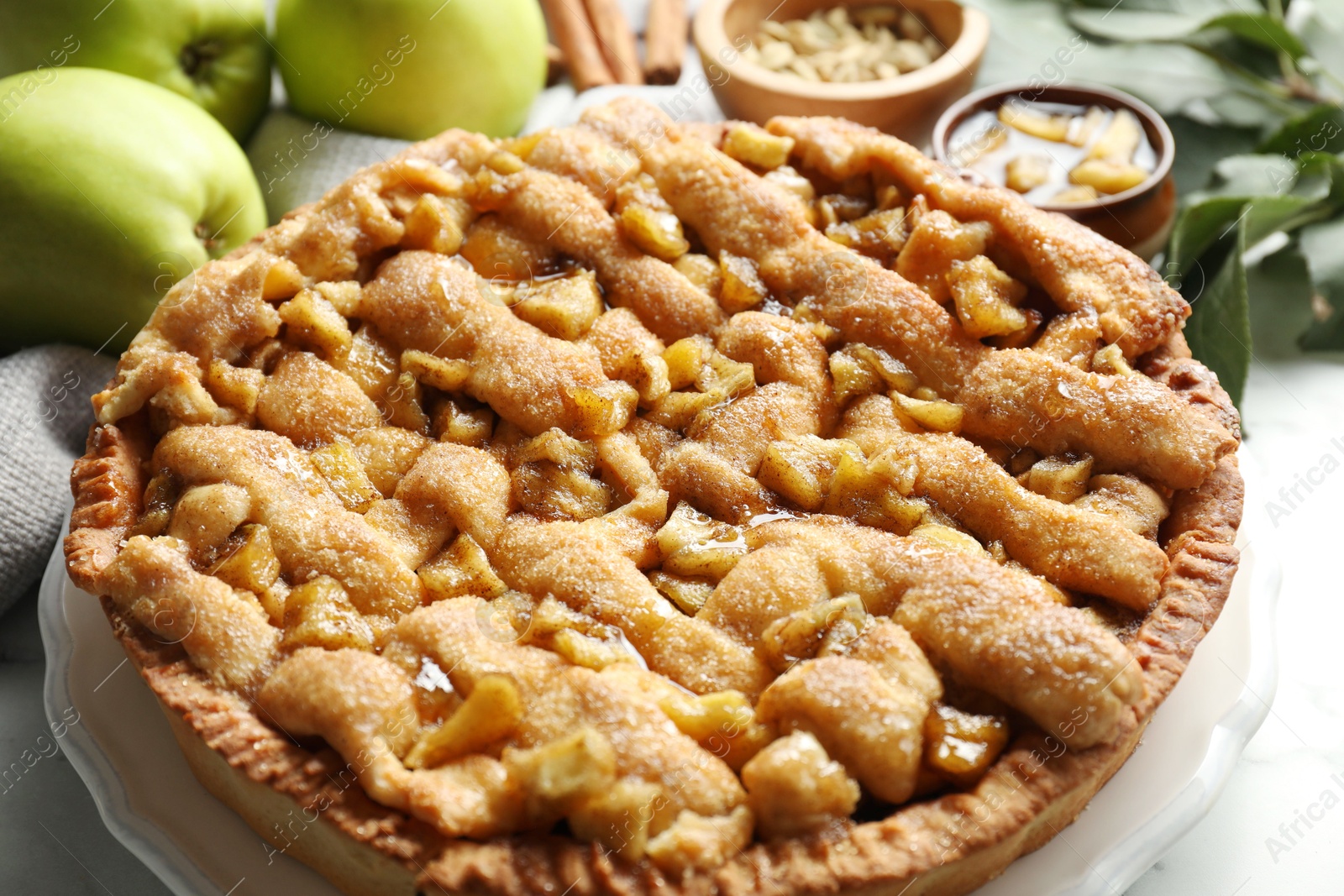 Photo of Homemade apple pie and ingredients on white marble table, closeup